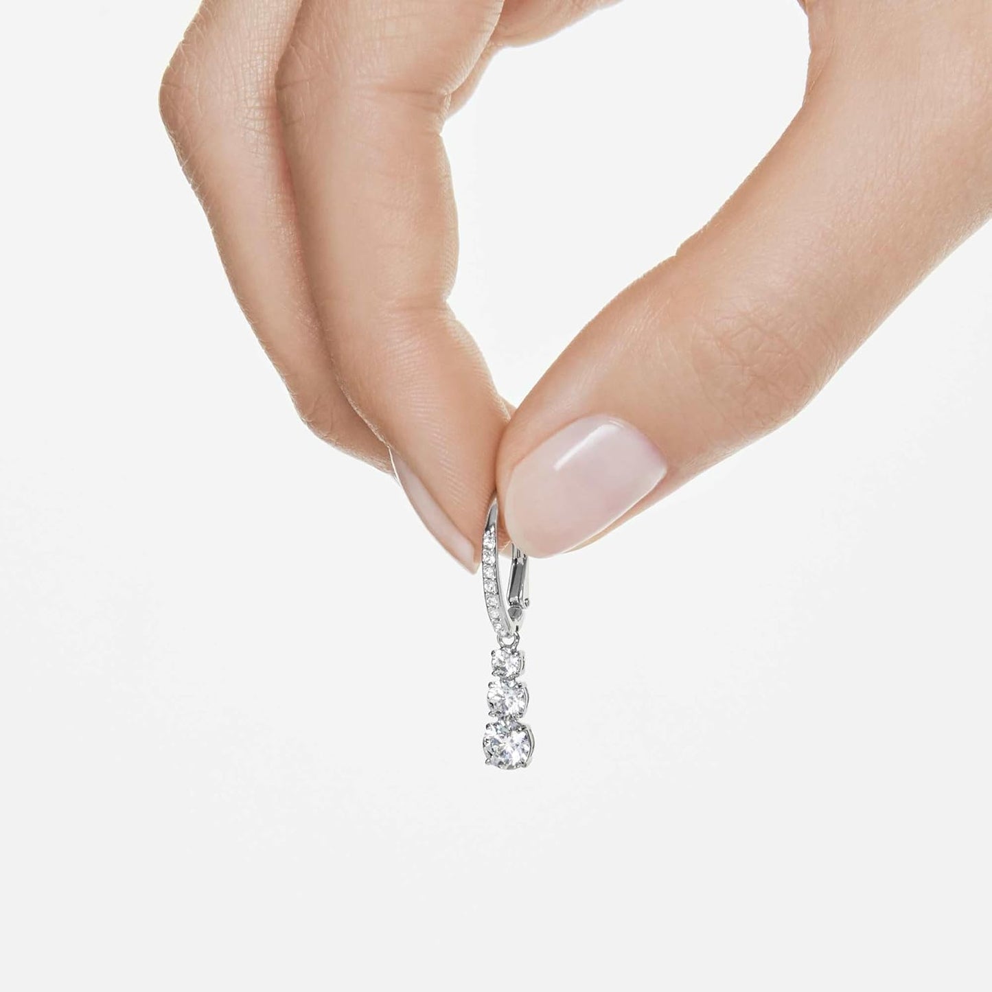 Hand holding Swarovski Stilla jewelry earrings featuring sparkling crystals and elegant design