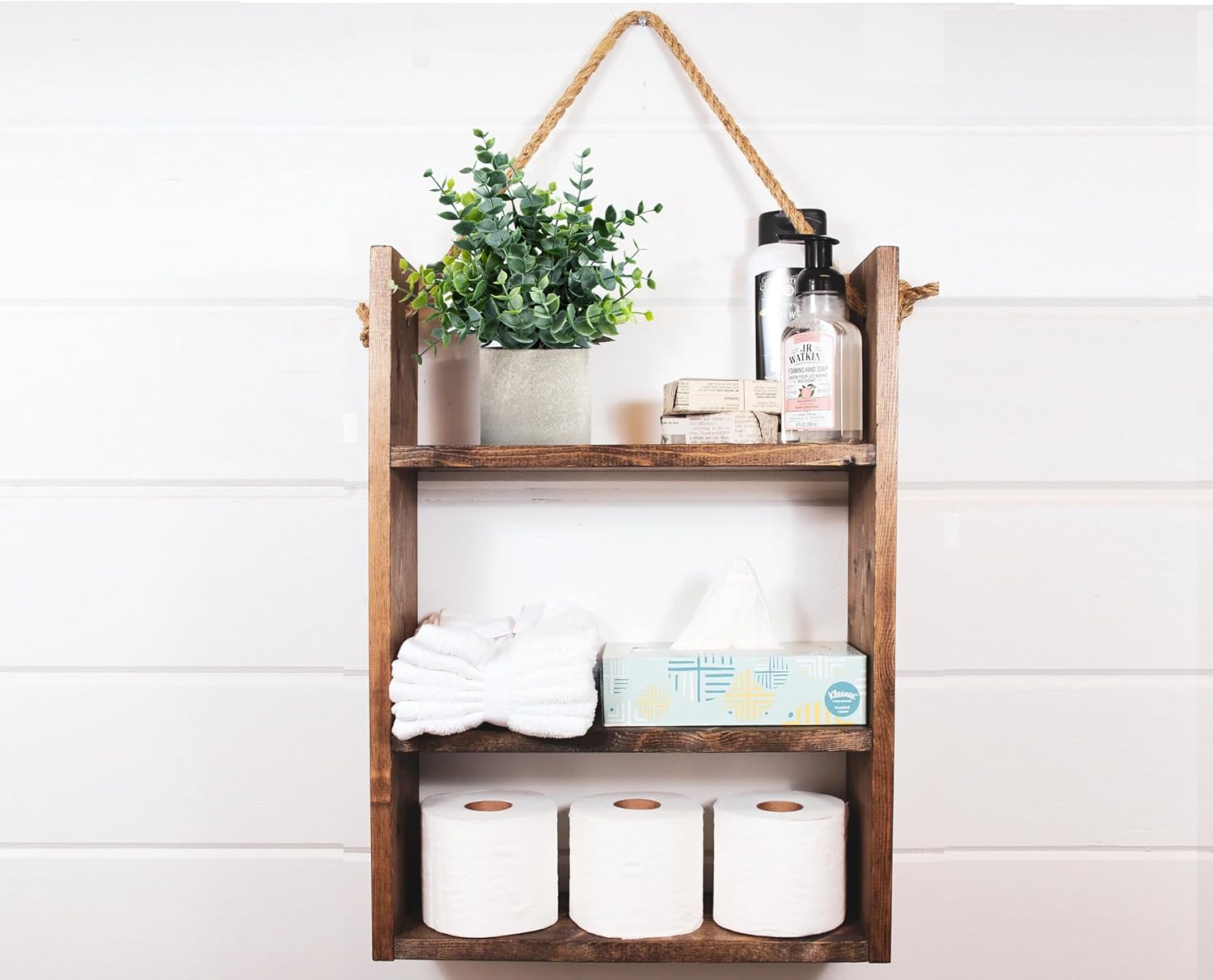 Decorative wooden shelf displaying artificial eucalyptus plants and bathroom essentials for stylish home decor