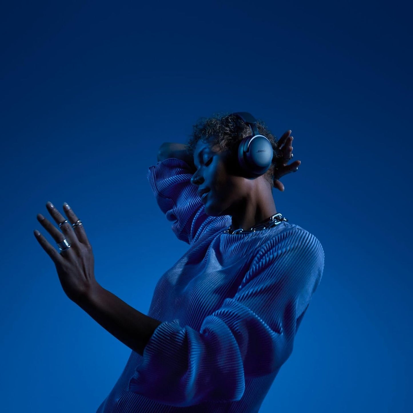 Woman enjoying music with Bose wireless headphones against a blue background