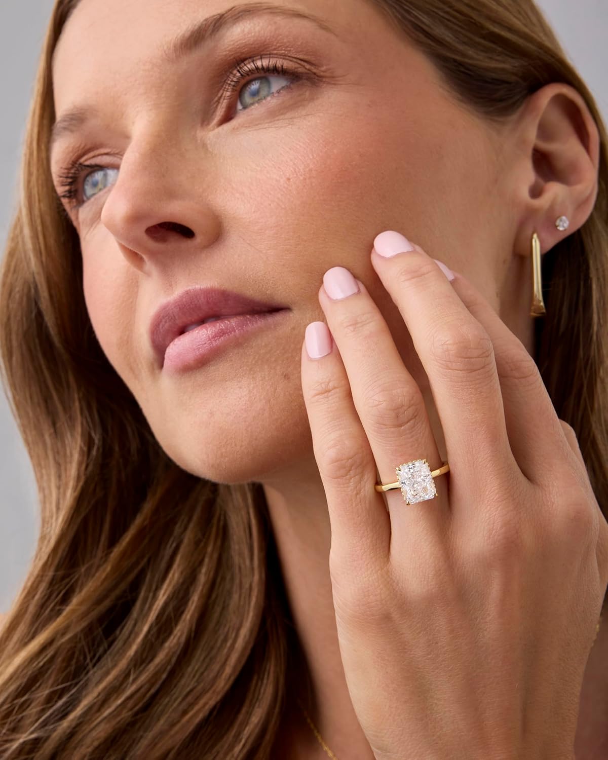 Model wearing a 14K gold plated engagement ring featuring a stunning center stone and elegant design