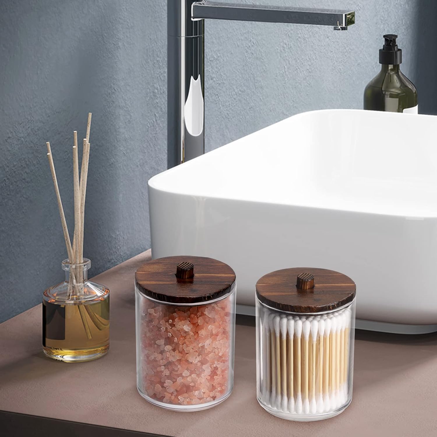 Clear canisters with wooden lids for cotton ball storage organizer in a modern bathroom setting